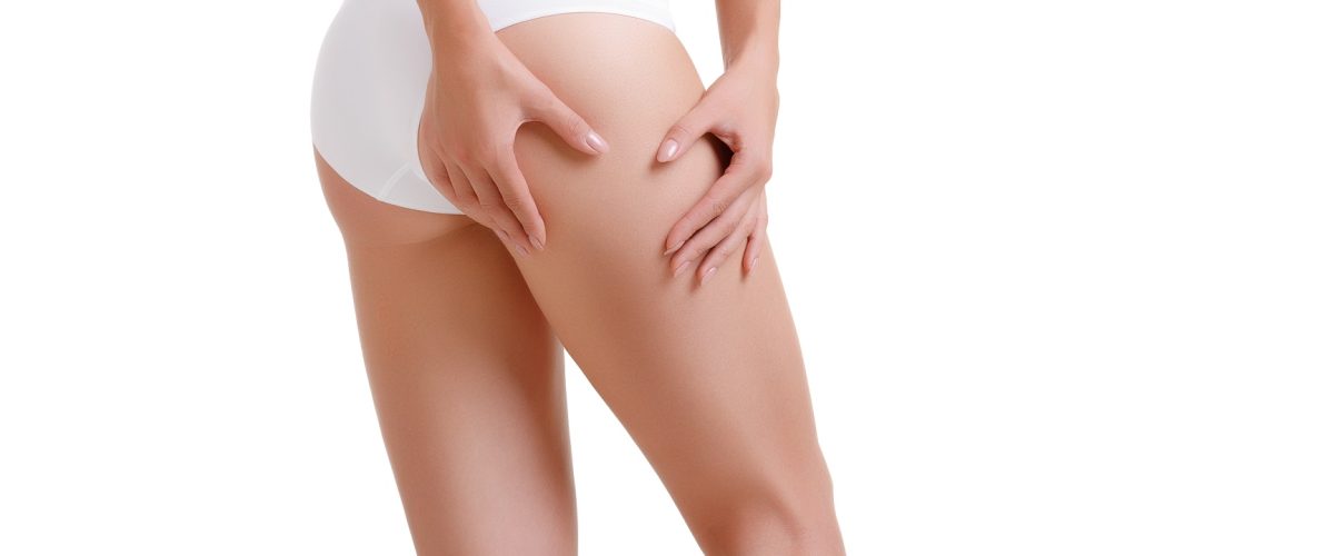 Female body care and beauty concept - close up of woman in underwear touching buttock over white background. Checking cellulite, woman hip, close up of beautiful female body legs, perfect woman figure